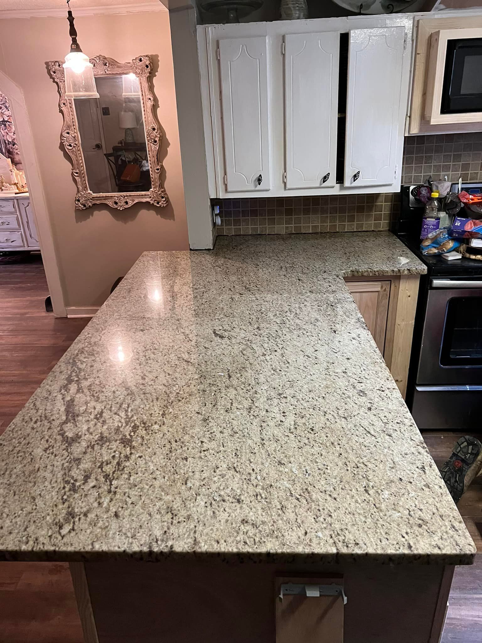 A kitchen with a large granite counter top and white cabinets.