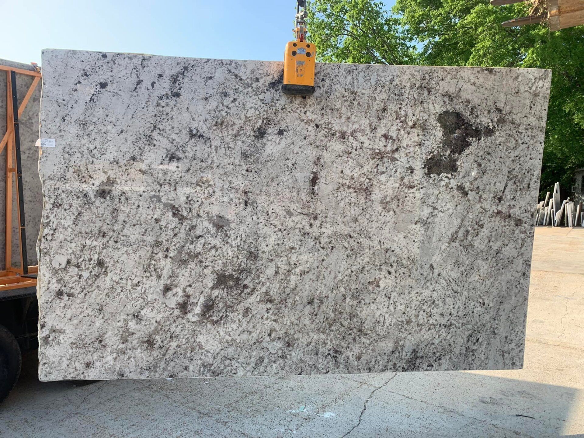 A large white granite slab is hanging from a crane.