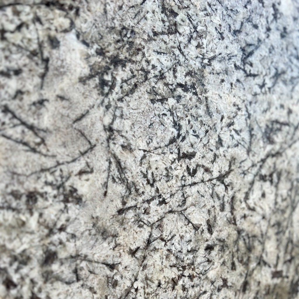 A close up of a white granite counter top with black spots.