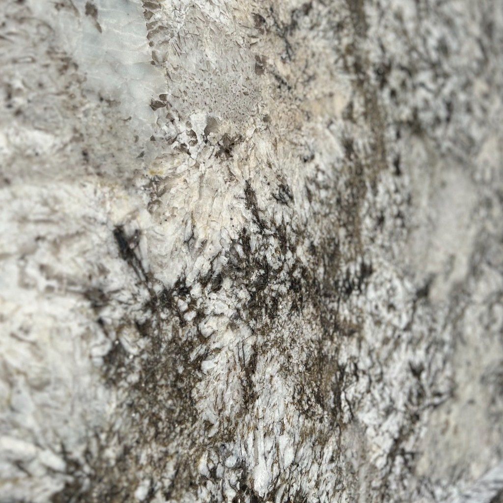 A close up of a white granite counter top with black spots.