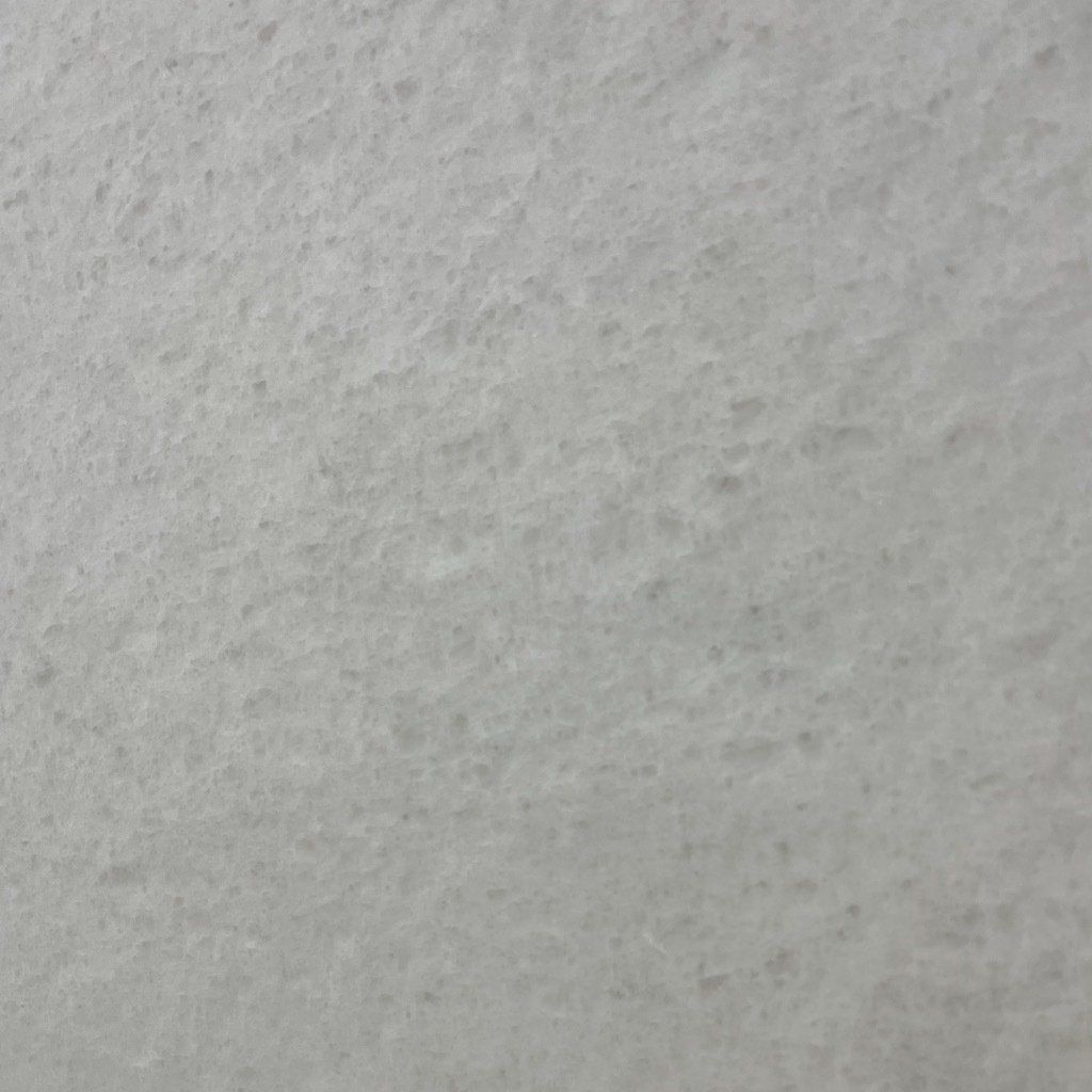 A close up of a white tile with a grainy texture.