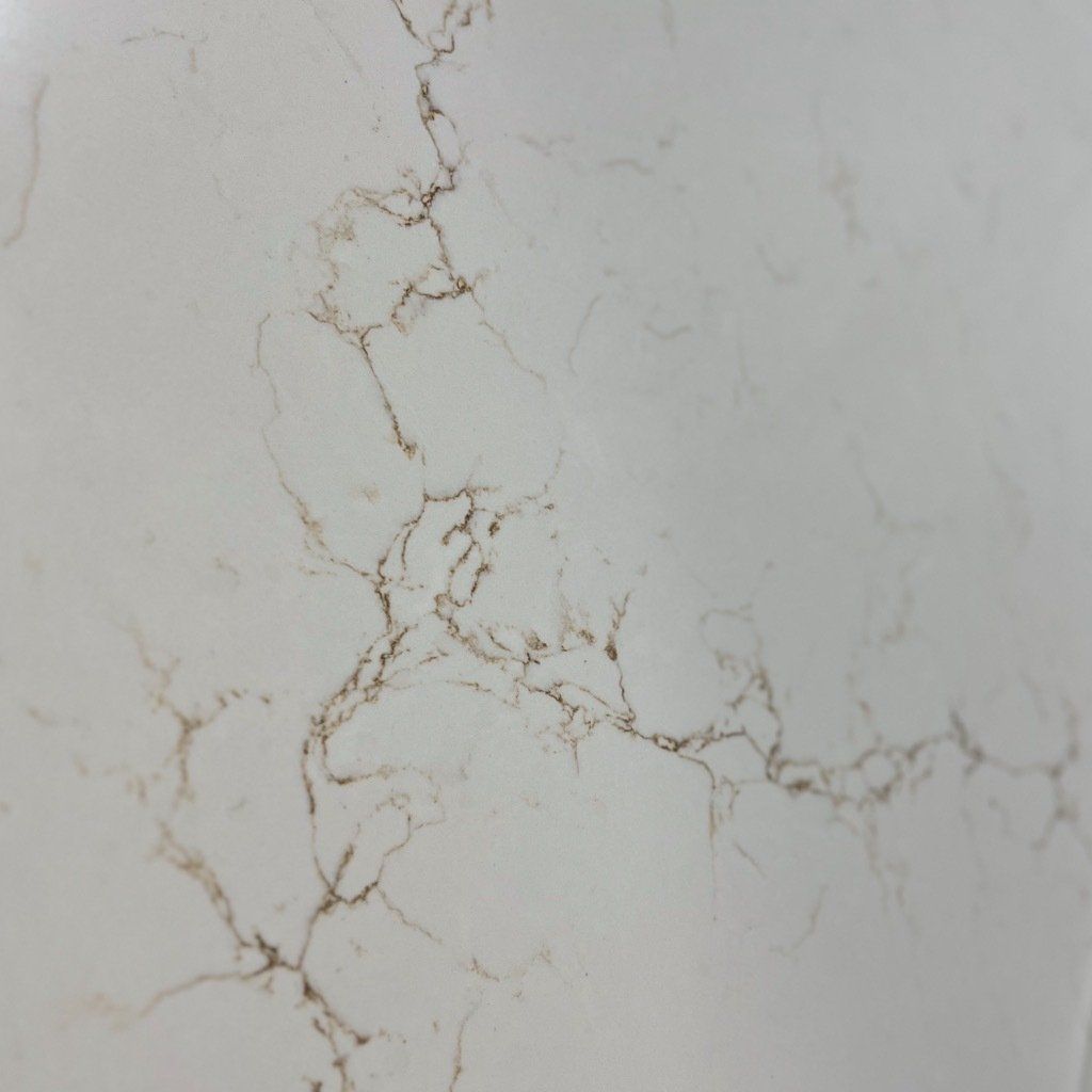 A close up of a white marble counter top with brown veins.