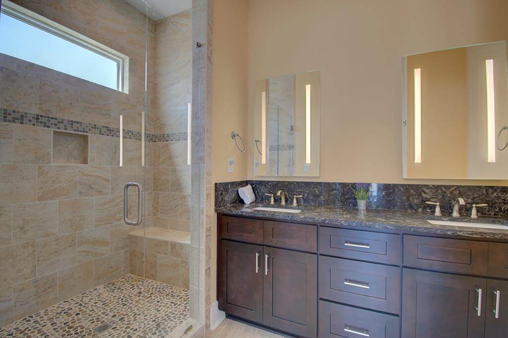 A bathroom with two sinks and a walk in shower