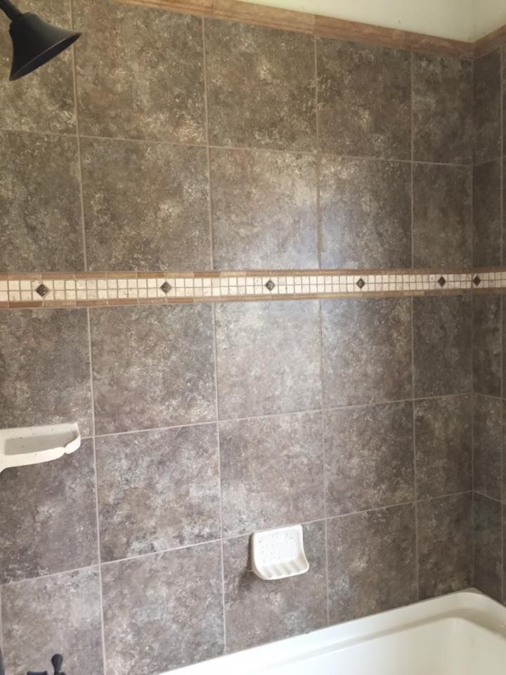 A bathroom with tiled walls and a shower head