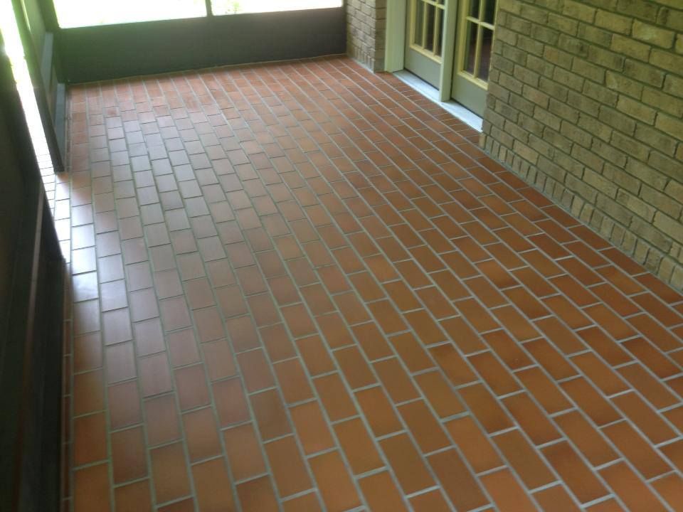 A screened in porch with a brick floor