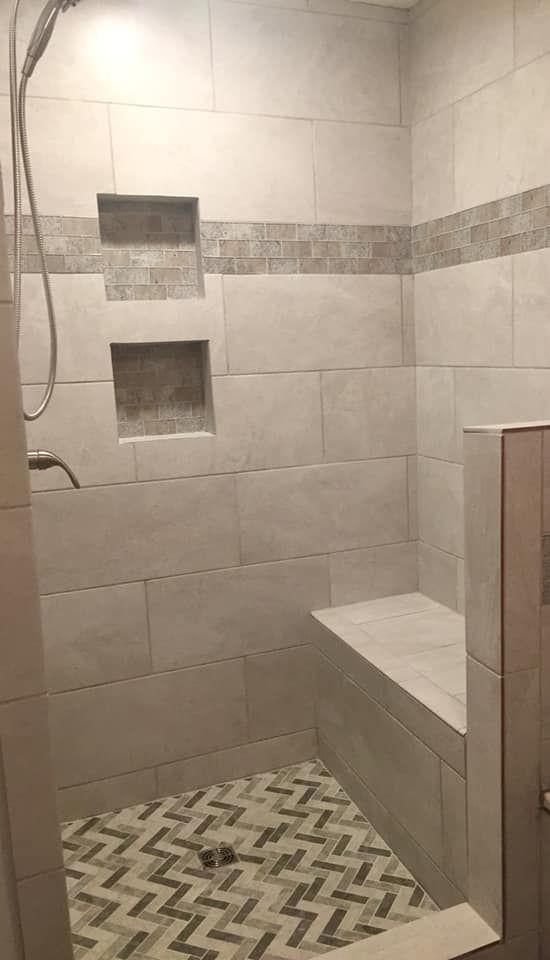 A shower with a bench and a shower head.
