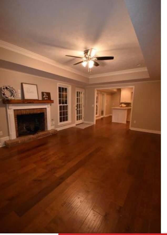 A living room with hardwood floors , a fireplace and a ceiling fan.