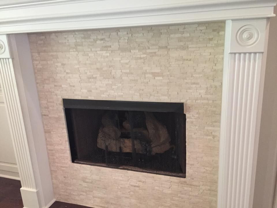 A fireplace with a black screen and a white mantle in a living room.
