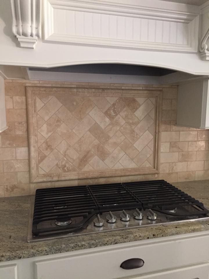 A stove top oven is sitting on top of a granite counter in a kitchen.