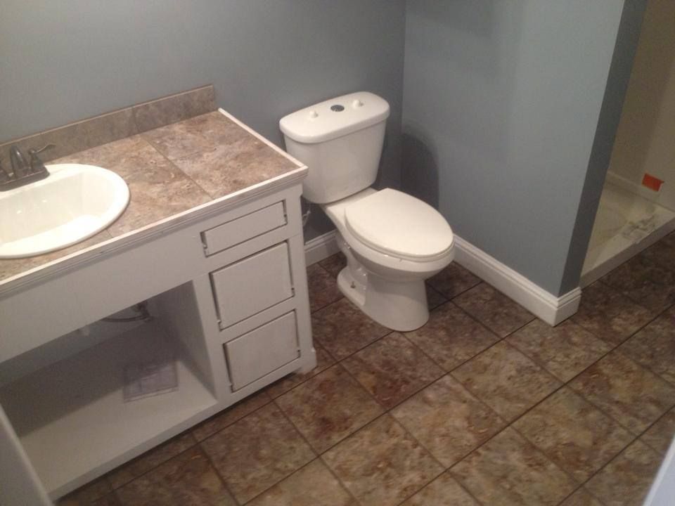 A bathroom with a toilet , sink and shower.