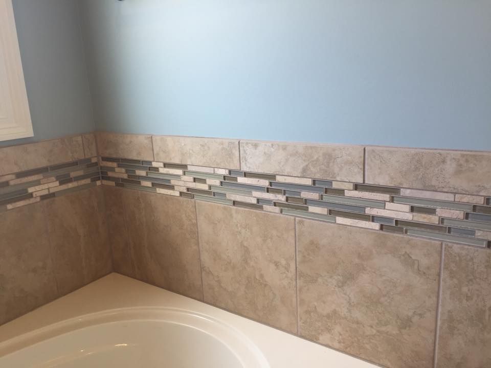 A bathroom with a bathtub and a tiled wall.