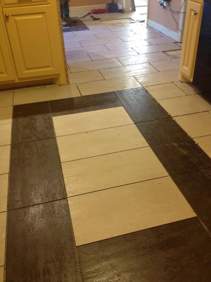 A kitchen floor with a brown and white tile pattern