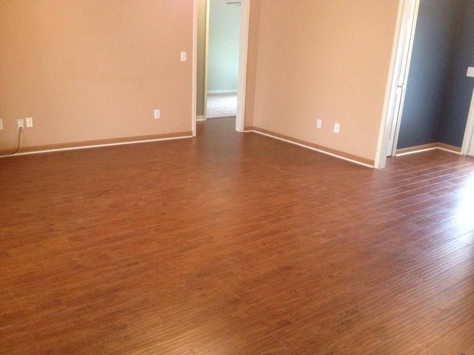 An empty living room with hardwood floors and a doorway leading to a bedroom.