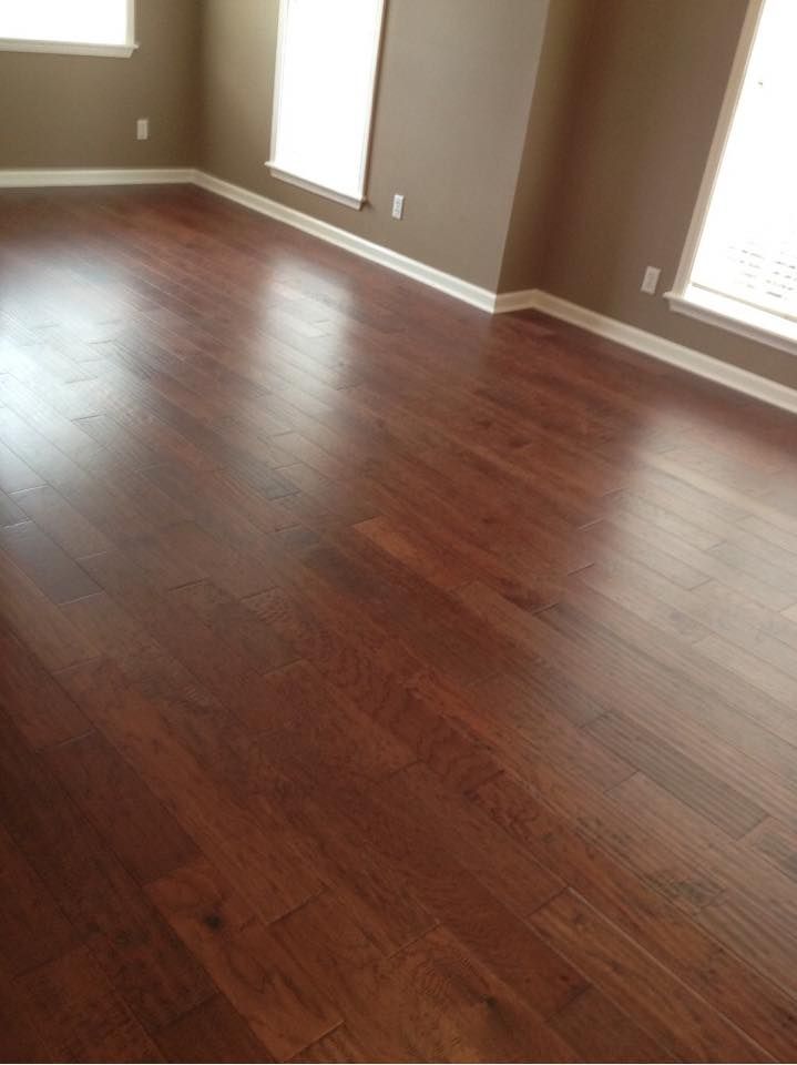 A living room with hardwood floors and two windows.
