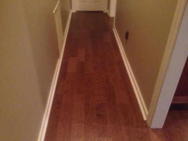 A hallway with hardwood floors and white trim