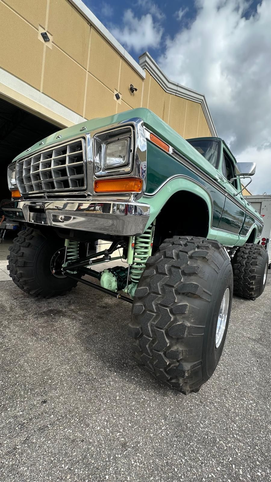 Green and chrome lifted vintage pickup truck with large tires.