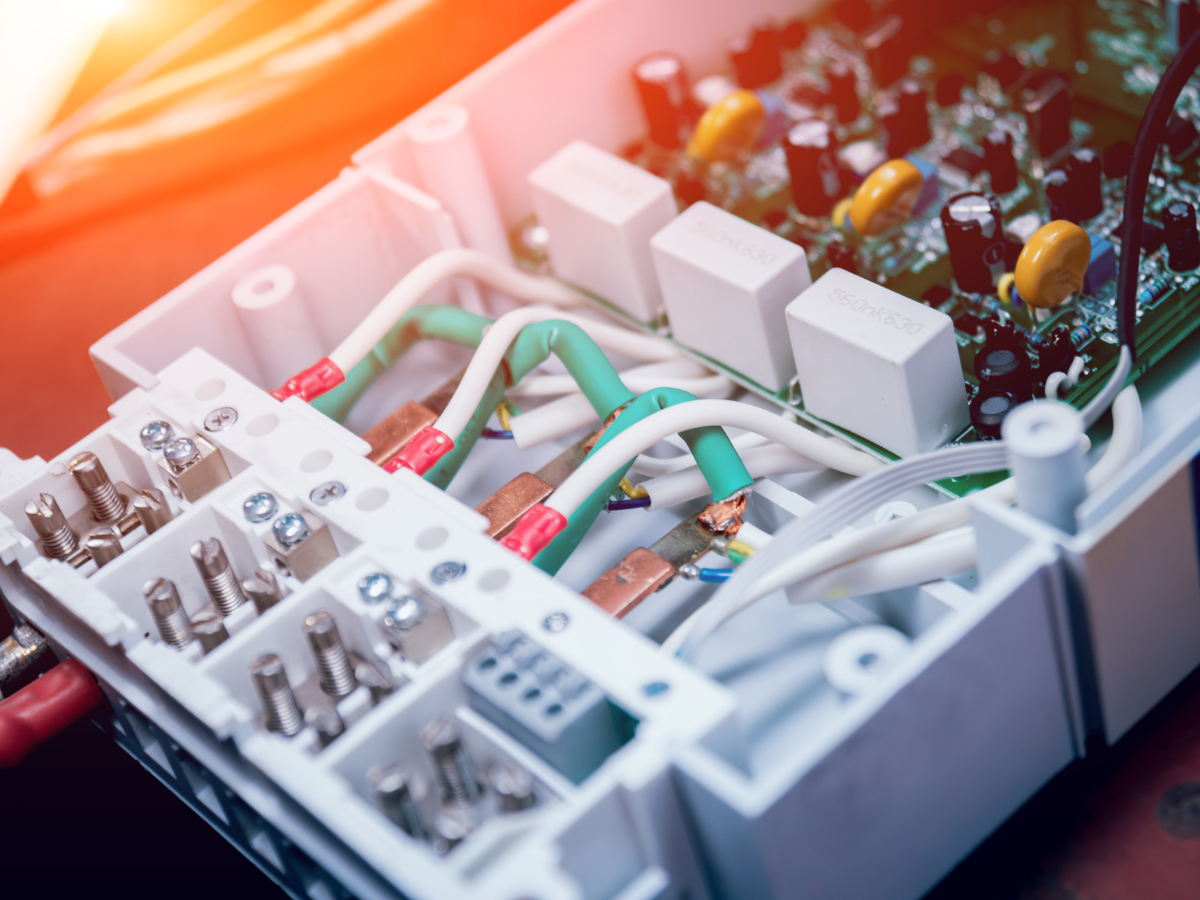 Open electrical panel with green, white, and red wires, connecting to a circuit board and components.