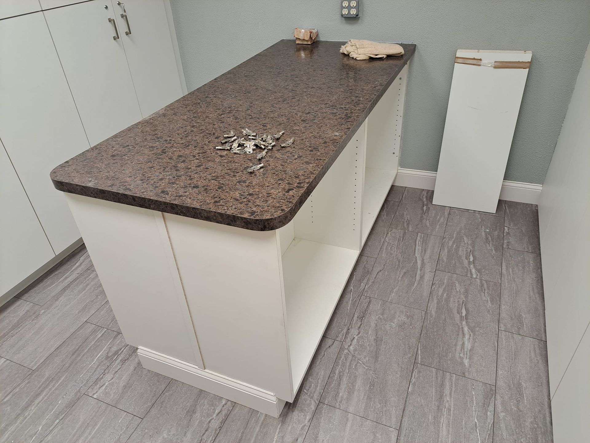 A kitchen island with a granite counter top and white cabinets.