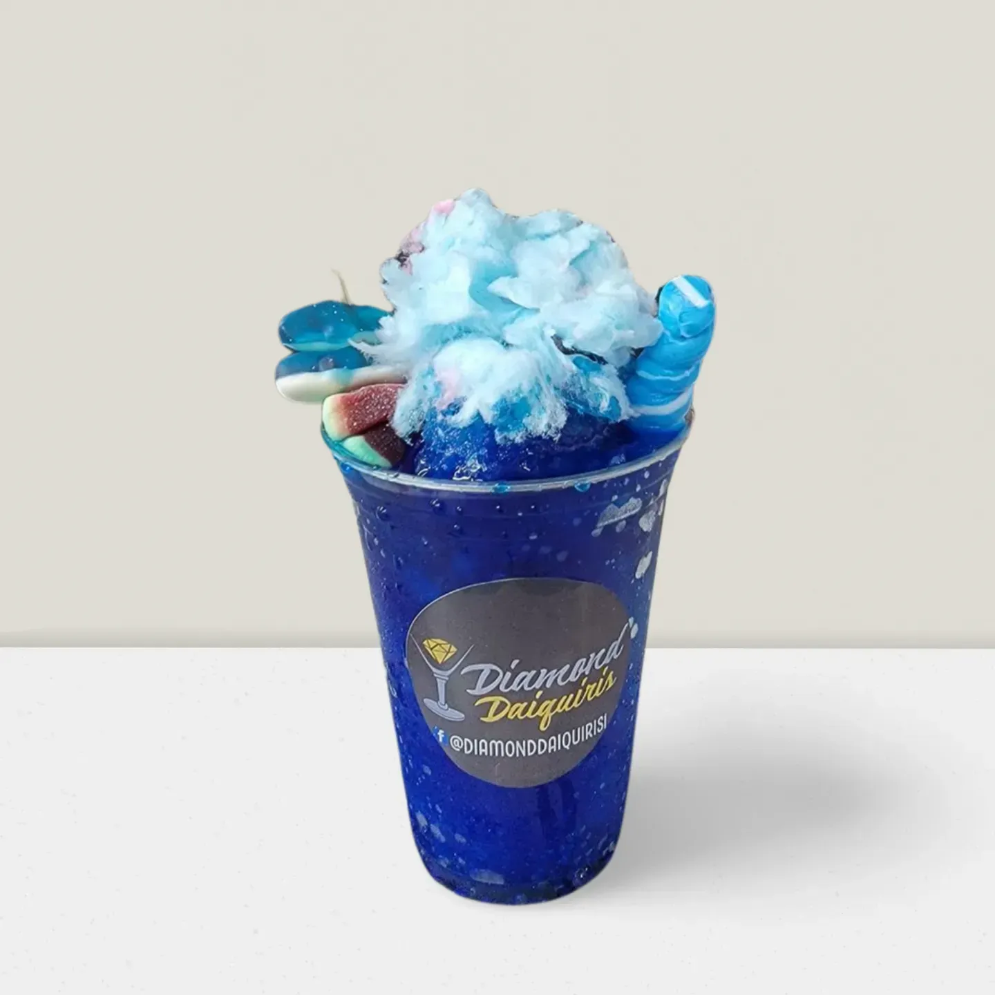 Blue shaved ice dessert in a blue cup with whipped topping and syrup