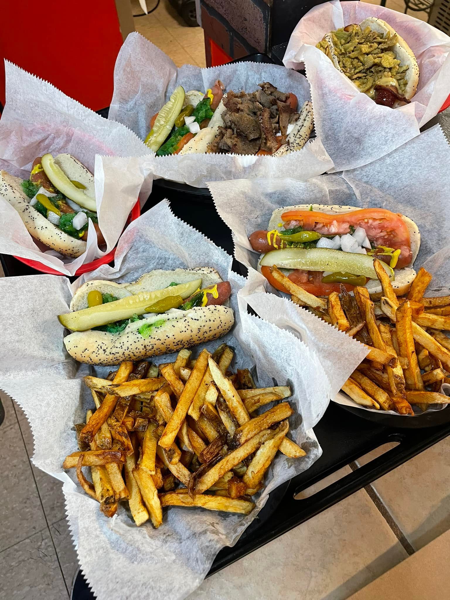 Assorted sandwiches and fries in paper baskets on a table at a casual restaurant.