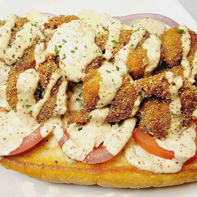 Open-faced sandwich with tomato, chicken, breadcrumbs, and creamy sauce on toasted bread