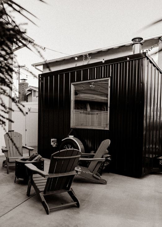 a black and white photo of a mobile sauna with chairs in front of it