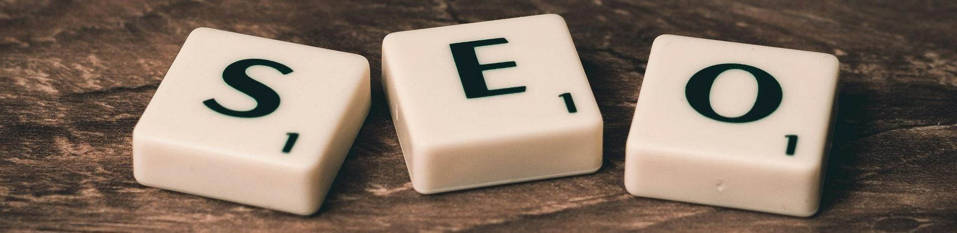 The word seo is written on scrabble tiles on a wooden table.
