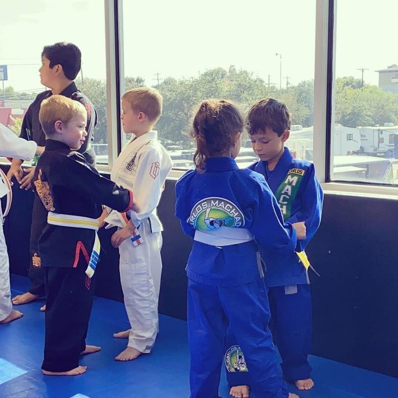 a group of kids are standing in front of a window wearing martial arts uniforms