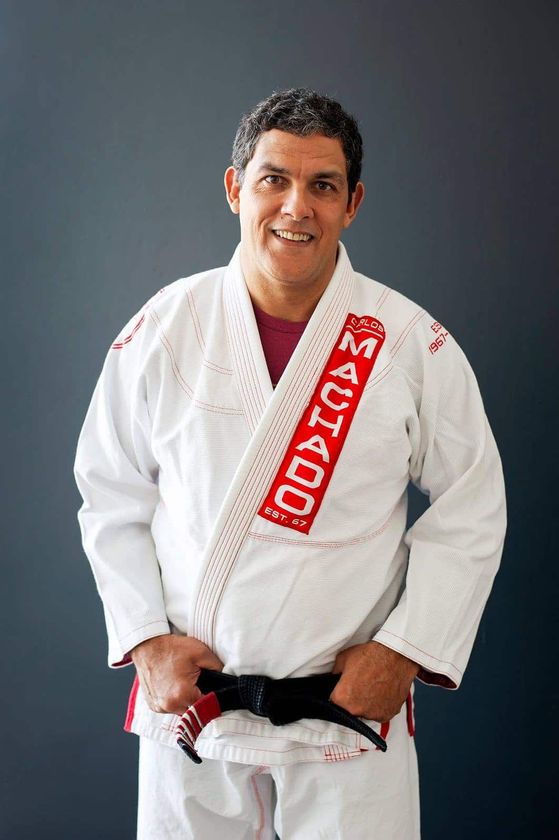a man in a white karate uniform is holding a black belt .