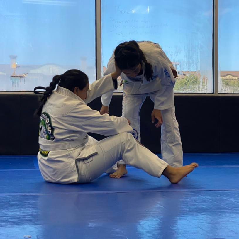 two women are practicing martial arts on a blue mat
