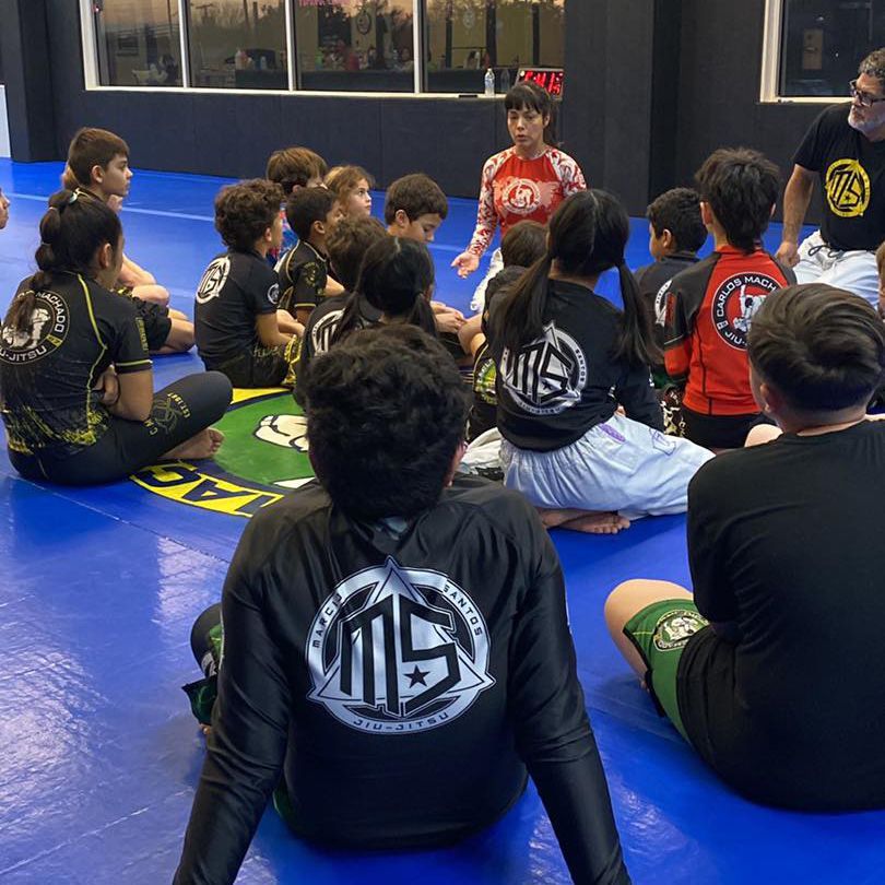 two young boys are wrestling on a mat and one of the boys is wearing a black karate uniform with the word karate on it