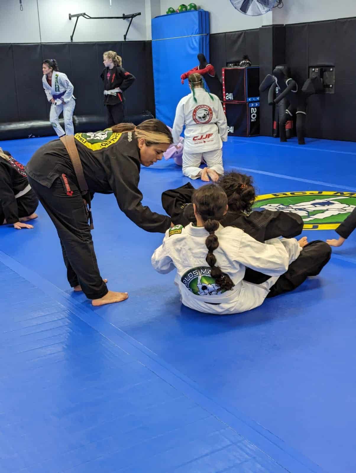 a group of people are practicing martial arts on a blue mat in a gym .