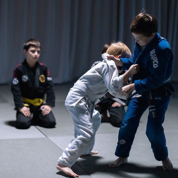 a group of young boys are practicing jiu jitsu on a mat .