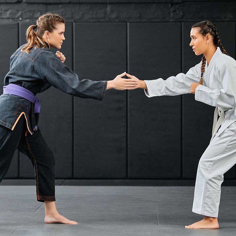 two women in karate uniforms are standing next to each other
