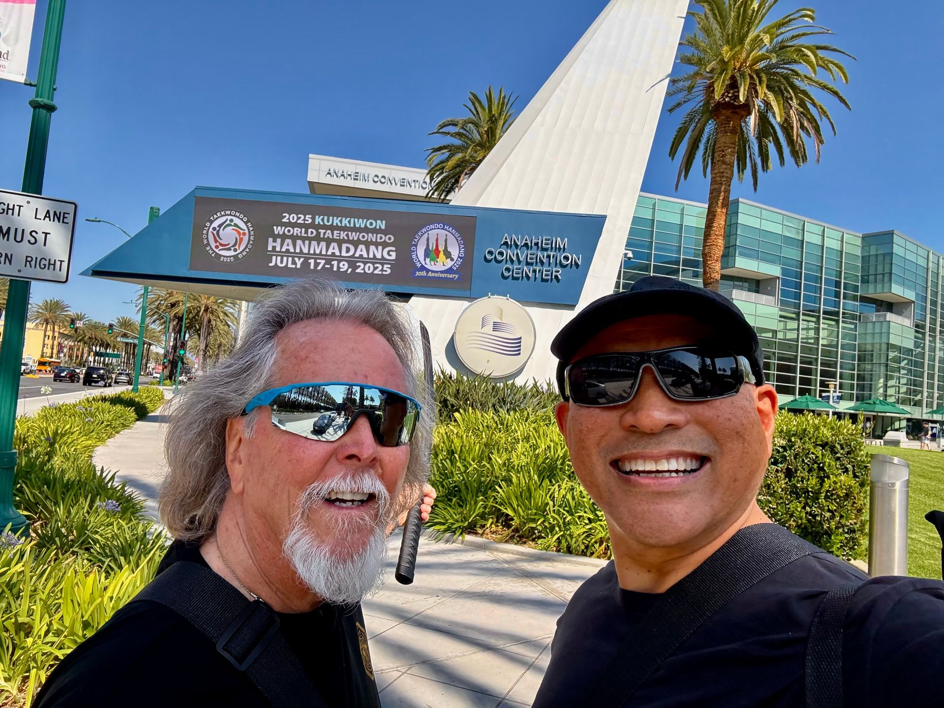Two men selfie in front of Huntington Beach, CA convention center. Sign: 