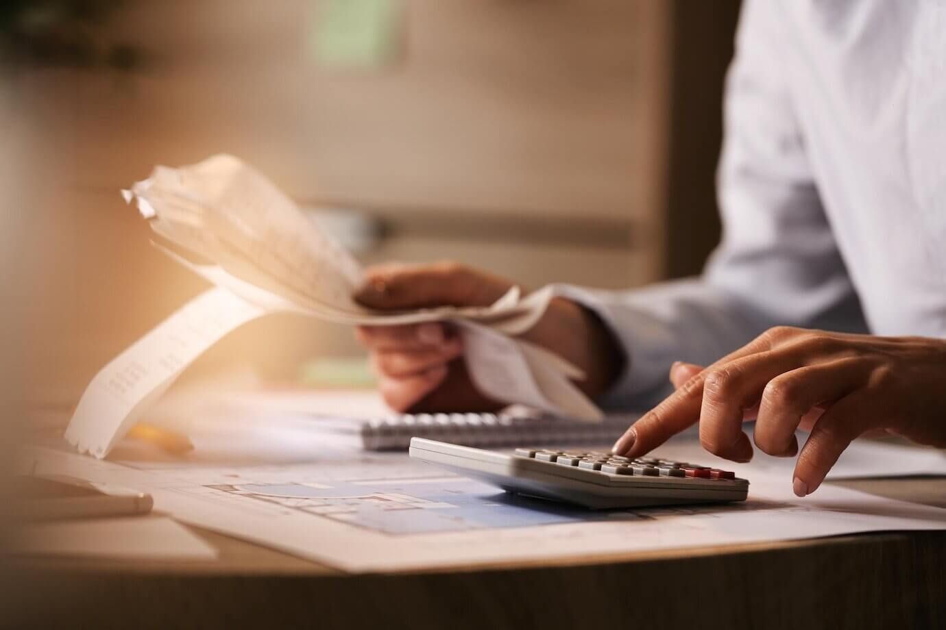 Una persona está usando una calculadora mientras sostiene una hoja de papel.