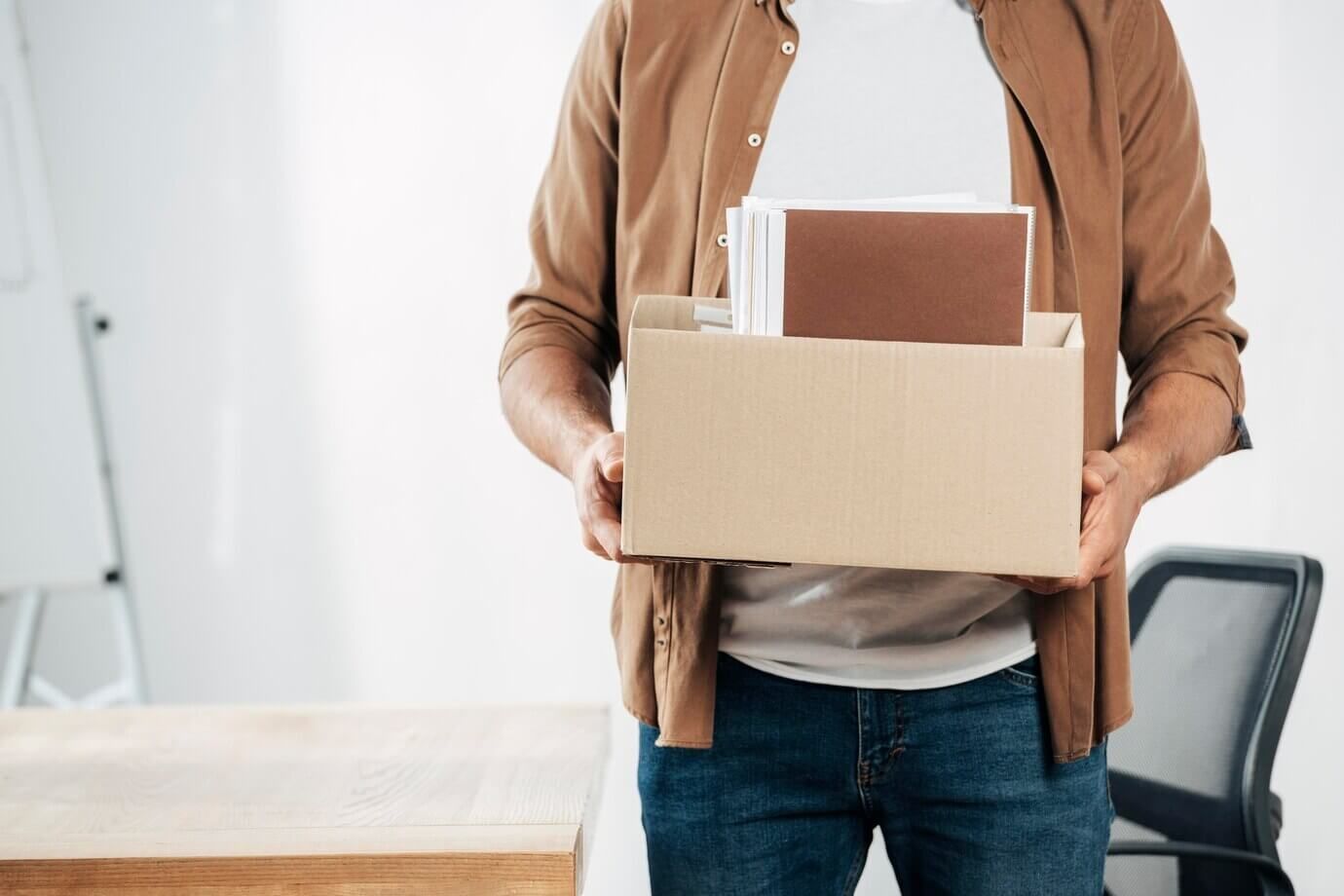 Un hombre sostiene una caja de cartón con sus pertenencias dentro.