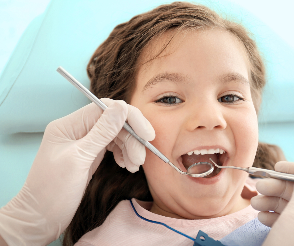 A young girl at the dentist, mouth open, being examined with dental tools; light blue background.