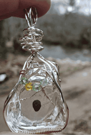 A person is holding a wire wrapped pendant in their hand.