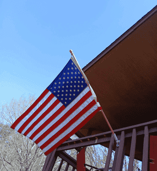 An american flag is hanging from a pole on a balcony