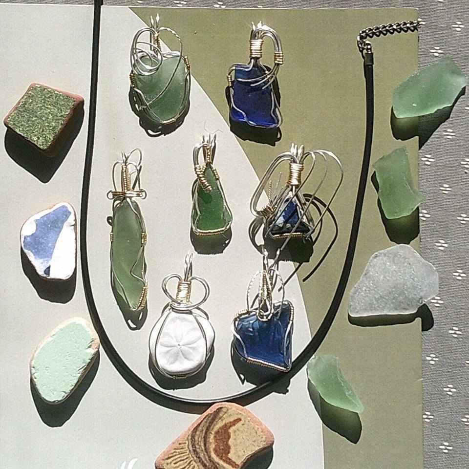 A necklace is surrounded by sea glass and rocks