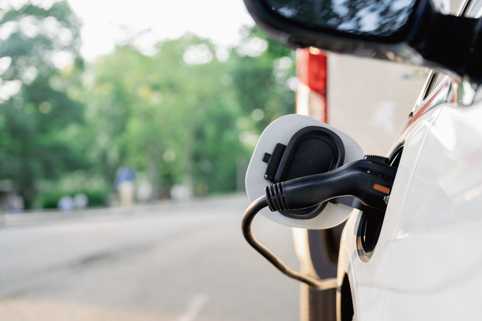 A white electric car is being charged at a charging station.
