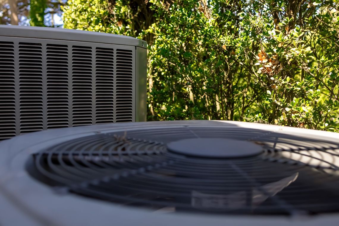 A close up of an air conditioner with trees in the background