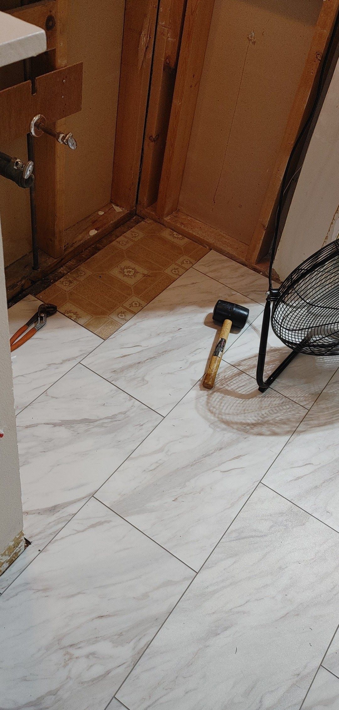 A hammer is sitting on the floor next to a chair.