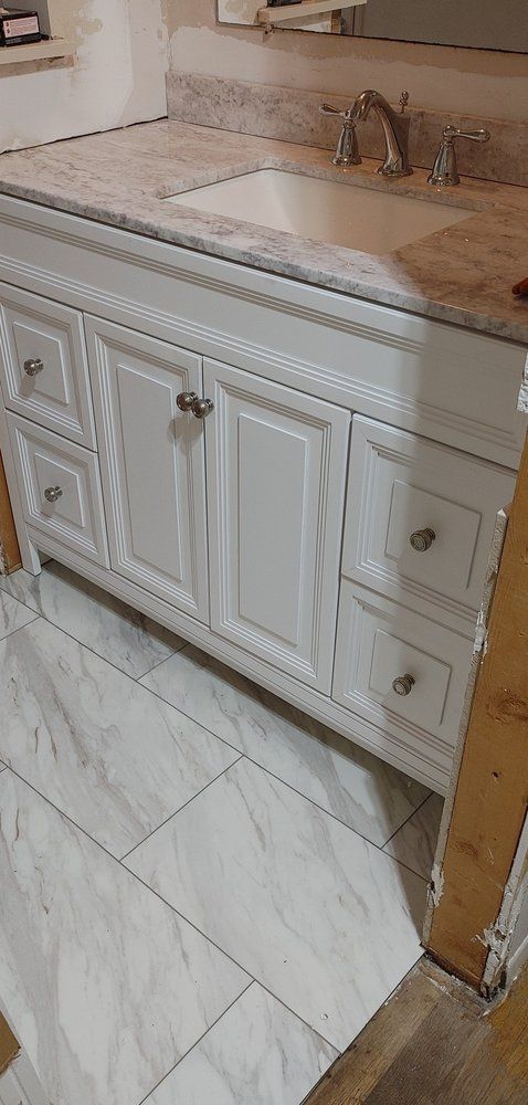 A bathroom vanity with a sink and a marble counter top.