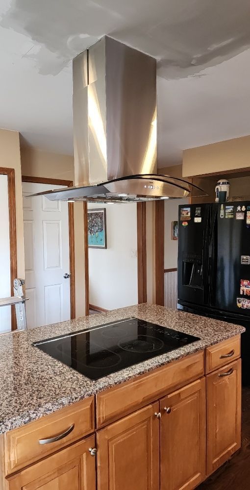 A kitchen with a stove top oven and a refrigerator.