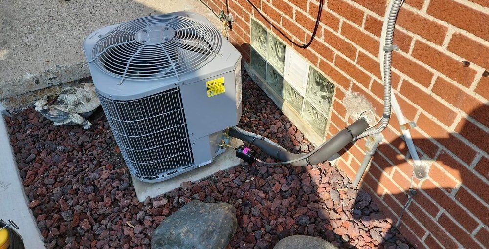 An air conditioner is sitting on the side of a brick building.