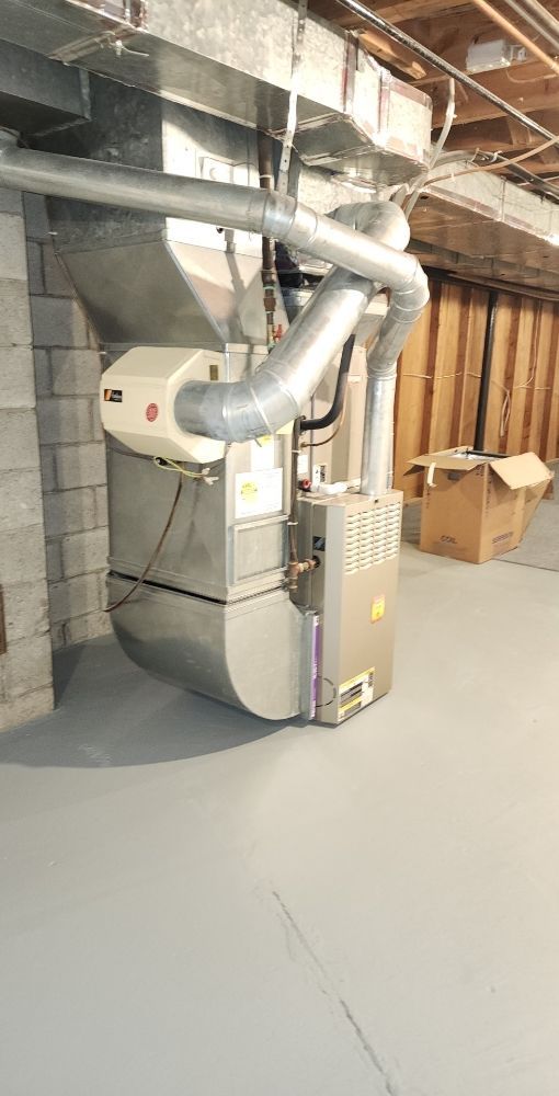 A basement with a furnace and a box on the floor.