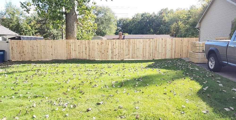 A truck is parked in front of a wooden fence in a yard.