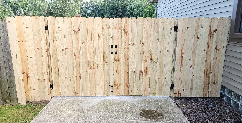 A wooden fence is sitting on top of a concrete driveway next to a house.